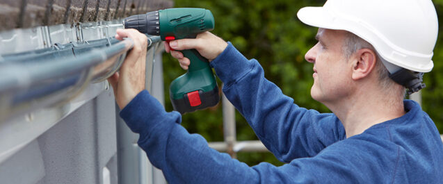 man in hardhat installing gutters