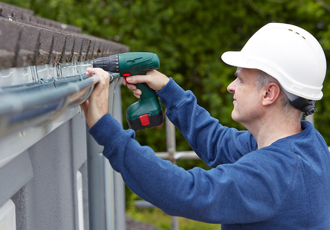 man in hardhat installing gutters
